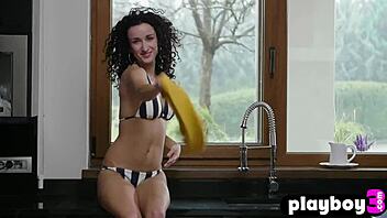 Lucy M, a charming petite model with curly hair, flaunts her alluring small breasts in the kitchen