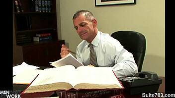Gay men engaging in sexual activity in an office setting, with emphasis on tattoos and oral pleasure