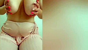 Young cutie in pink dress teases her big tits on camera