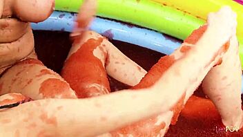 Cheerful babes play with jello in the pool and finger each other