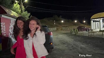 Two teen girls pissing publicly near their car.