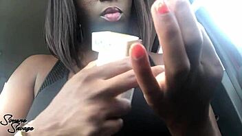 An ebony woman smokes a cigarette in the car.