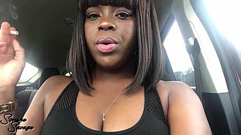 An ebony woman smokes a cigarette in the car.