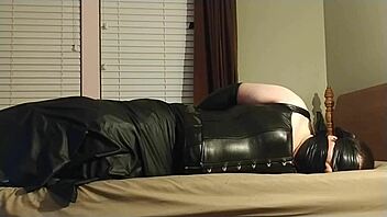 the crossdresser ties himself up in leather bondage, choking and gagging with boots