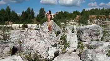 Topless mature woman dances gracefully in white stone quarry