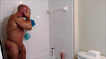 Soap and oil cover muscular body in steamy shower session