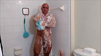 Soap and oil cover muscular body in steamy shower session