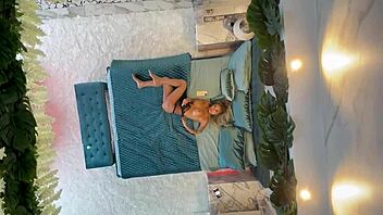 Monika Fox poses naked on the bed, showcasing her pierced nipples and big tits.