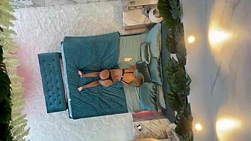 Monika Fox poses naked on the bed, showcasing her pierced nipples and big tits.