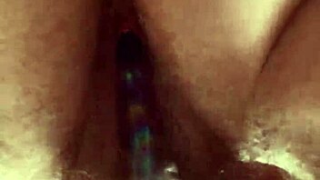 Close-up view of hairy pussy getting worked by a glass dildo in solo play.  