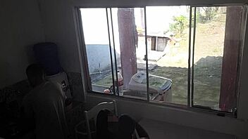 Man with hearing issue washes dishes while wife chats with friend in kitchen