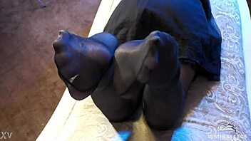 sexy goddess in black pantyhose with rose print on heels teases you with her feet