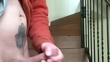 Amateur guy masturbates with huge cock in apartment garage while neighbor chats on phone nearby.