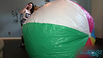 Behind the scenes, black MILF inflates a mega beach ball on the sunny shore.