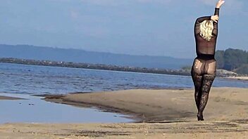 In a black style outfit she flashes confidently on the sunny beach enjoying the outdoor vibe. Nature surrounds her as she poses freely in heels and pantyhose.