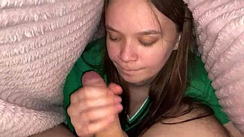 In the cozy bedroom, a young brunette girlfriend climbed under the blanket to deliver a deep blowjob to her roommate