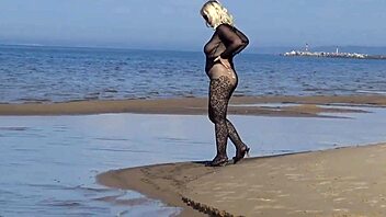 In a black style outfit she flashes confidently on the sunny beach enjoying the outdoor vibe. Nature surrounds her as she poses freely in heels and pantyhose.