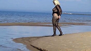 In a black style outfit she flashes confidently on the sunny beach enjoying the outdoor vibe. Nature surrounds her as she poses freely in heels and pantyhose.