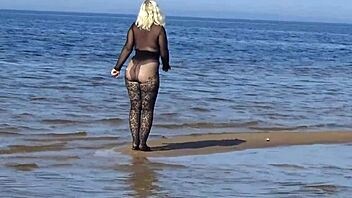 In a black style outfit she flashes confidently on the sunny beach enjoying the outdoor vibe. Nature surrounds her as she poses freely in heels and pantyhose.