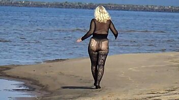 In a black style outfit she flashes confidently on the sunny beach enjoying the outdoor vibe. Nature surrounds her as she poses freely in heels and pantyhose.
