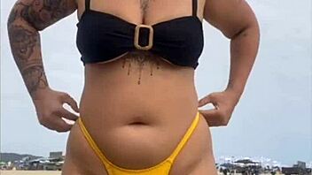 Wearing a tight yellow bikini that highlights her figure to draw attention at the beach