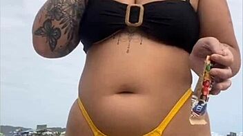 Wearing a tight yellow bikini that highlights her figure to draw attention at the beach