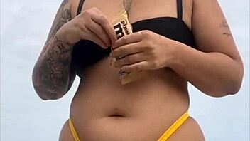 Wearing a tight yellow bikini that highlights her figure to draw attention at the beach
