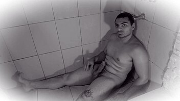 muscular guy strokes big cock in golden shower bath